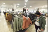  ??  ?? A shopper wearing a face mask checks the bargains at the Glendale Galleria in Glendale, Calif., on Friday.