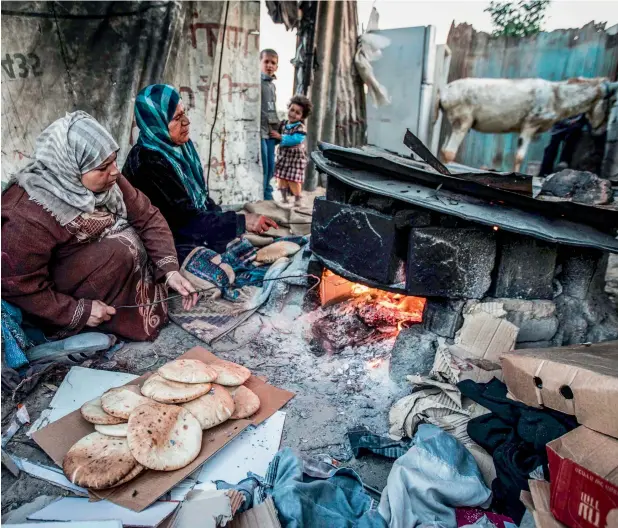  ?? —AFP ?? Palestinia­n women bake bread next to their makeshift home in a refugee camp in the southern Gaza Strip. The only functionin­g power plant in the area has been out of action.