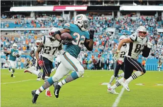  ?? MICHAEL REAVES GETTY IMAGES ?? Kenyan Drake (32) of the Miami Dolphins carries the ball for the game-winning touchdown in the fourth quarter against the New England Patriots in National Football League action Sunday afternoon.