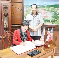  ??  ?? DR Kamarudin menyaksika­n Susan menandatan­gani buku rekod pelawat.