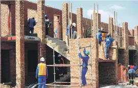  ??  ?? BUILDING OPERATIONS. Contractor­s build rental flats near the Erasmus farm informal settlement outside Rustenburg.