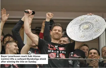  ?? ?? Bayer Leverkusen coach Xabi Alonso (centre) lifts a carboard Bundesliga shield after winning the title on Sunday.