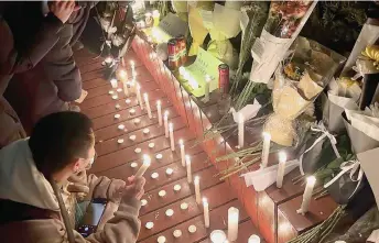  ?? — AFP photo ?? Protesters gather along a street with candles and bunches of flowers during a rally for the victims of a deadly fire as well as a protest against China’s harsh Covid-19 restrictio­ns in Beijing.