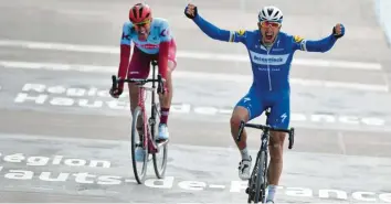  ?? Foto: dpa ?? Philippe Gilbert (rechts) aus Belgien überquert jubelnd als Sieger die Ziellinie, während hinter ihm der Deutsche Nils Politt Zweiter wird.