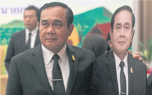  ?? THANARAK KHUNTON ?? Prime Minister Prayut Chan-o-cha poses with a cut-out of himself. His government is facing criticism over its handling of the economy.