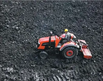  ?? WU HE / FOR CHINA DAILY ?? A man operates a tractor to crush coal, one of the fuels used by the thermal power industry, in Huaibei, Anhui province.