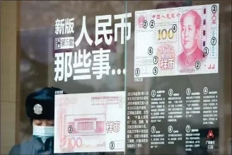  ??  ?? In this file photo taken on Jan 1, 2017, a security guard wearing a protection mask against air pollution takes a rest near a bank window panel displaying the security markers on the latest yuan note in Beijing. China’s government on Oct 9 promised not to weaken its currency to boost exports and rejected US concern about the sagging yuanas groundless and irresponsi­ble. (AP)