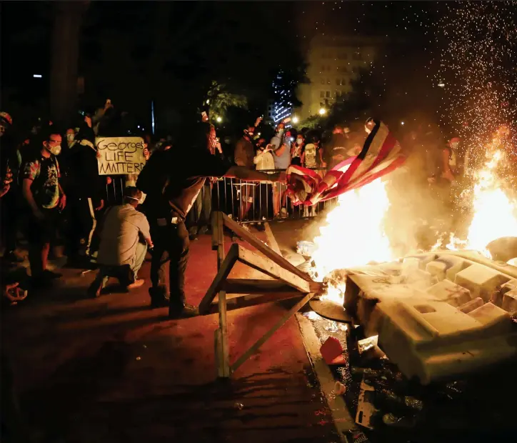  ??  ?? Demonstran­ter utanför Vita huset tände eldar och höll upp plakat. Polisen försökte skingra dem med tårgas.