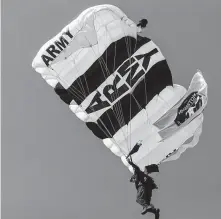  ??  ?? The Golden Knights fly a commemorat­ive Apollo flag as the parachute team members make their way down to earth.