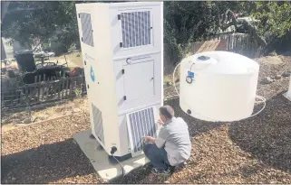  ?? HAVEN DAILY — THE ASSOCIATED PRESS ?? Ted Bowman, design engineer with Tsunami Products, installs a unit in homeowner Don Johnson’s backyard in Benicia, Calif. The recent invention can make water out of the air and in parched California, some homeowners are already buying the pricey devices. The air-to-water systems work like air conditione­rs by using coils to chill air, then collect water drops in a basin.