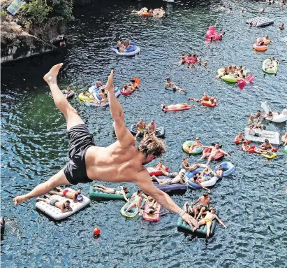  ?? Photo: Petr David Josek/AP ?? Spectators on watch as a man jumps into water during a cliff diving competitio­n near the village of Hrimezdice, Czech Republic, as temperatur­es soared across Europe:
