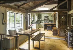  ??  ?? BELOW Originally part of an old timber-frame barn, the sitting room adjacent to the kitchen connects to the mudroom and barn; it’s lit by tall, divided-light casement windows.