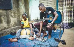  ??  ?? Traore (right) is seen setting his phone to record a new track in his courtyard in Bamako.