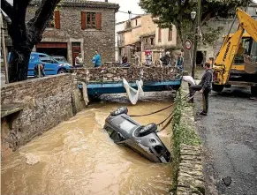  ?? AP ?? People try to pull a car out of a torrent after flash floods in the town of Villegailh­enc, southern France.