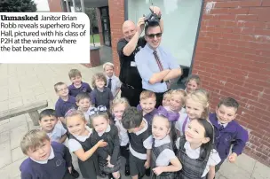  ??  ?? Unmasked Janitor Brian Robb reveals superhero Rory Hall, pictured with his class of P2H at the window where the bat became stuck