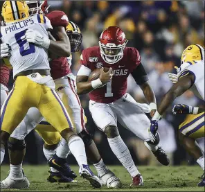  ?? NWA Democrat-Gazette/CHARLIE KAIJO ?? Arkansas freshman quarterbac­k KJ Jefferson (center) rushes through a hole against top-ranked LSU during the first quarter Saturday at Tiger Stadium in Baton Rouge. Jefferson, who made his first start as a Razorback, threw for 105 yards in the Razorbacks’ 56-20 loss.