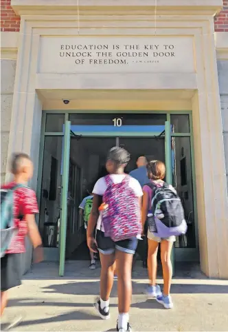  ?? [ERIC ALBRECHT/DISPATCH] ?? Students at Columbus’ Clinton Elementary School walked in for the first day of class last month. The Clintonvil­le school features a quote from George Washington Carver above the door.