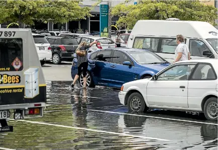  ?? PHOTO: BRADEN FASTIER/STUFF ?? A motorist tries to keep her feet dry as king tide flooding surrounds her car.