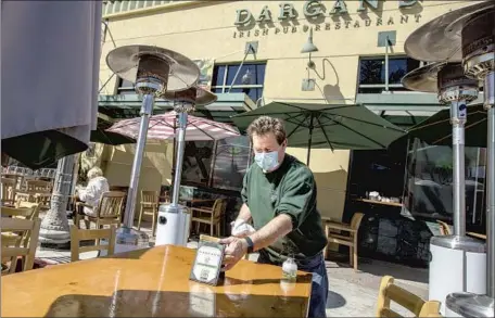  ?? Photograph­s by Brian van der Brug Los Angeles Times ?? DARGAN'S OWNER Liam Sherlock cleans a table Tuesday. Dargan’s closed on St. Patrick’s Day 2020, typically one of its busiest days.