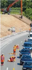  ??  ?? Bauarbeite­r markieren die Straße um, daneben staut sich der Verkehr.