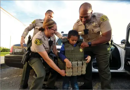  ?? Christian Monterrosa/ The Signal (See additional photos at signalscv.com) ?? Sheriff’s deputies from the Santa Clarita Valley Sheriff’s Station let Gregory Jones, 5, try on a bulletproo­f tactical vest at his birthday party at Mountasia Family Fun Center in Canyon Country on Saturday. Members of the SCV community, sheriff’s station and fire department came out to attend the birthday party for the boy who was recently diagnosed with Autism Spectrum Disorder.