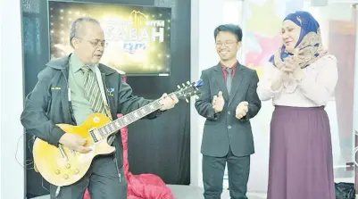  ??  ?? ALI (kiri) memetik gitar sebagai gimik pelancaran Album Pertama Kombo RTM Sabah sambil diperhatik­an Matlan (tengah) dan Malinaziah (kanan).