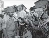  ?? AP/MUKHTAR KHAN ?? Kashmiri women talk to a policeman after paramilita­ry troops opened fire on a car at a police barricade Saturday in Srinagar, India.