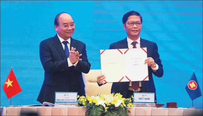  ?? HAU DINH/AP ?? Vietnamese Prime Minister Nguyen Xuan Phuc, left, applauds as Minister of Trade Tran Tuan Anh holds a signed document during a virtual signing ceremony of the Regional Comprehens­ive Economic Partnershi­p trade agreement in Hanoi, Vietnam, on Nov. 15.