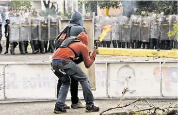  ?? AFP / Getty Images ?? Estos activistas se preparan a lanzar un coctel molotov contra miembros de la Guardia Nacional durante una protesta en San Cristóbal, capital del estado de Táchira, en el occidente de Venezuela.