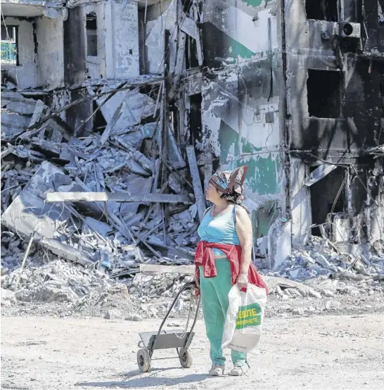  ?? REUTERS ?? A woman stands near a residentia­l building destroyed during the Ukraine-russia conflict in the southern port city of Mariupol, Ukraine, on Thursday.