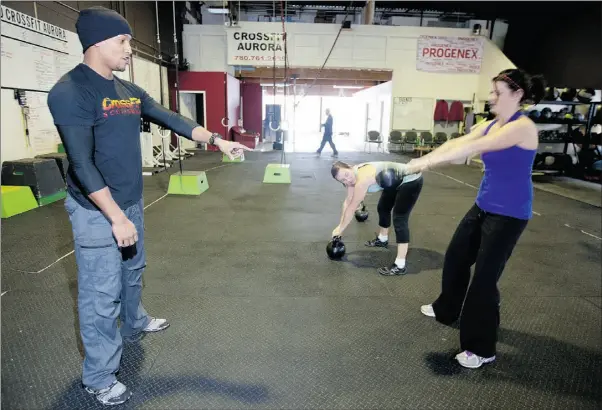  ?? Photos: Greg Southam, The Journal ?? Trainer Ed Martin helps Kelly Meeking as she takes part in a tough new fitness regime called Crossfit at the Crossfit Aurora gym in Edmonton.