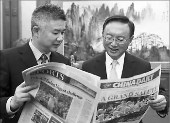  ?? XU JINGXING / CHINA DAILY ?? State Councilor Yang Jiechi (right) reads a copy of China Daily as Sun Shangwu, China Daily’s Deputy Editor-in-Chief, describes the editing process of the newspaper after an interview in Beijing.