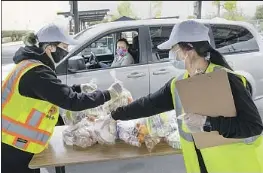  ?? Mel Melcon Los Angeles Times ?? DIANA MENDOZA, left, and Esmeralda Diaz prepare food for distributi­on at San Fernando Senior High in 2020. In the car is Angie Perez of San Fernando.