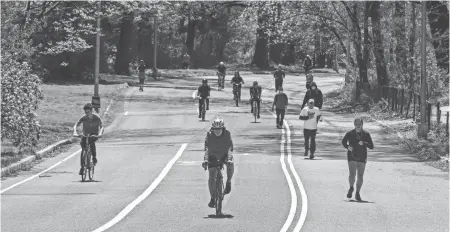  ?? STEPHANIE KEITH/GETTY IMAGES ?? People jog and ride bicycles in Prospect Park on April 28 in the Brooklyn borough in New York City. New York City Parks Department has kept the parks open, but required people to practice distancing by staying 6 feet apart from each other.