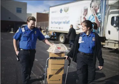  ?? NWA Democrat-Gazette/CHARLIE KAIJO ?? Dennis Weeks (left) and Sydney Johnson with the Transporta­tion Security Administra­tion pull a cart loaded with food Friday at Northwest Arkansas Regional Airport in Highfill.