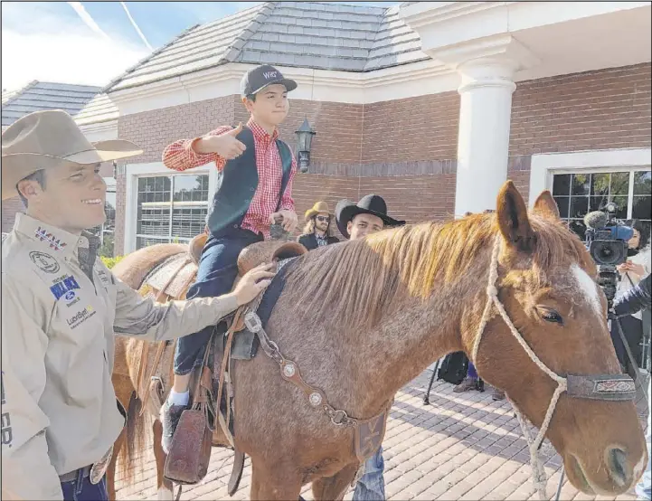  ?? Patrick Everson Las Vegas Review-Journal ?? Angelo Mayorga, 11, assures everyone Friday that he’s having a good time sitting on AJ, as world champion tie-down roper Caleb Smidt helps, during the Grant a Gift Autism Foundation’s annual event with the Wrangler National Finals Rodeo.