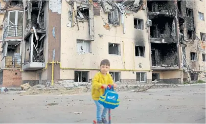  ?? REUTERS ?? Escena. Un nene juega con su monpatín frente a un edificio quemado y en escombros en Irpin.