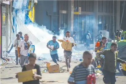  ?? ?? People run with merchandis­e amid unrest in Port Moresby, Papua New Guinea. PNG Prime Minister James Marape has declared a state of emergency after at least 15 people died in violent riots on Wednesday. Several Chinese citizens were lightly injured, with Chinese owned-stores vandalized and looted, the Chinese Embassy said. — AFP