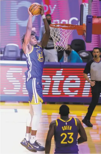  ?? Santiago Mejia / The Chronicle ?? Warriors center James Wiseman elevates for a dunk as teammate Draymond Green admires it.