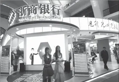  ?? WU CHANGQING / FOR CHINA DAILY ?? Salespeopl­e promote financial services at the stall of private-sector, listed China Zheshang Bank, which is headquarte­red in Hangzhou, Zhejiang province, at an internatio­nal finance expo in Beijing.