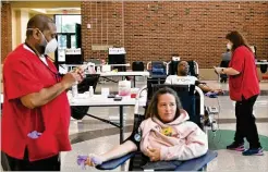  ??  ?? Above: Brandon Hastings donates during Buford City Schools’ blood drive at Buford Arena on Tuesday. The temperatur­es of donors were taken and other precaution­s were put in place.