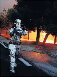  ??  ?? INFERNO Firefighte­r in flame resistant outfit at Rafina