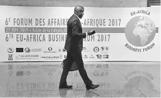  ?? — AFP photo ?? A man walks past a banner at the 6th EU-Africa Business Forum on November 27, 2017, in Abidjan, ahead of the Afican Union - European Union summit.