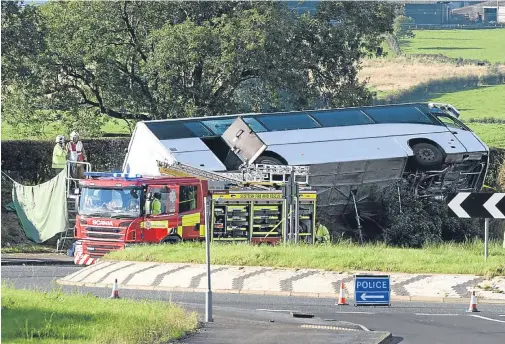  ??  ?? Firefighte­rs at the scene of the tragedy in East Ayrshire as the Rangers supporters’ coach lies on its side.