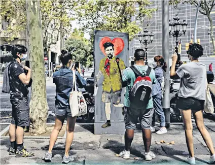  ??  ?? In the frame: Fans take pictures of the latest street artwork of Messi to appear in Barcelona