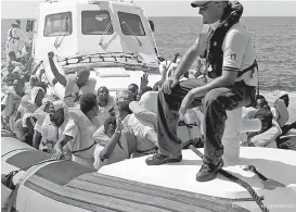  ?? Kenny Karpov/SOS Mediterran­ee via AP ?? ■ This photo taken Tuesday and released Wednesday by French NGO “SOS Mediterran­ee” shows migrants waving after being transferre­d from the Aquarius ship to Italian Coast Guard boats in the Mediterran­ean Sea.