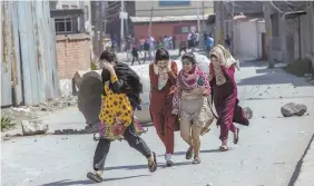  ??  ?? FIERCE FIGHTING: Deadly protests against Indian rule erupted in several parts of Kashmir yesterday. Residentia­l buildings go up in flames during a gun battle, top, and Kashmiri girls run for cover, above.