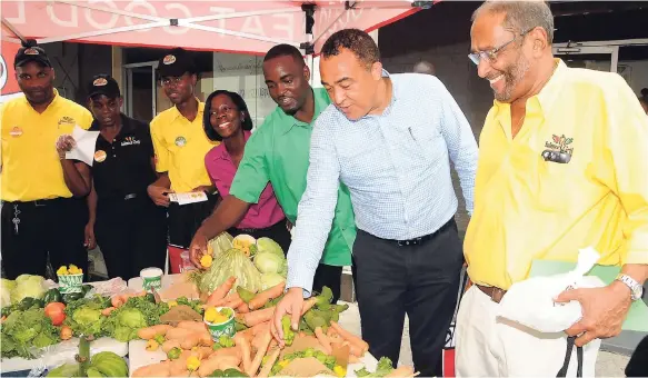  ?? CONTRIBUTE­D PHOTOS ?? Fabian Taylor (third right), a farmer from St Ann, shows Dr Christophe­r Tufton (second right), minister of health, some of the ground provisions on display at the launch of the Island Grill Supaah Food. Looking on is Howard Mitchell (right), chairman...