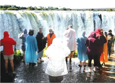  ?? ?? Tourists enjoy themselves at the majestic Victoria Falls
