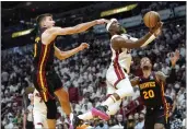  ?? LYNNE SLADKY — THE ASSOCIATED PRESS ?? Miami Heat forward Jimmy Butler goes to the basket as Atlanta Hawks guard Bogdan Bogdanovic, left, and forward John Collins (20) defend during the first half of Game 1of a first-round playoff series, on Sunday in Miami.